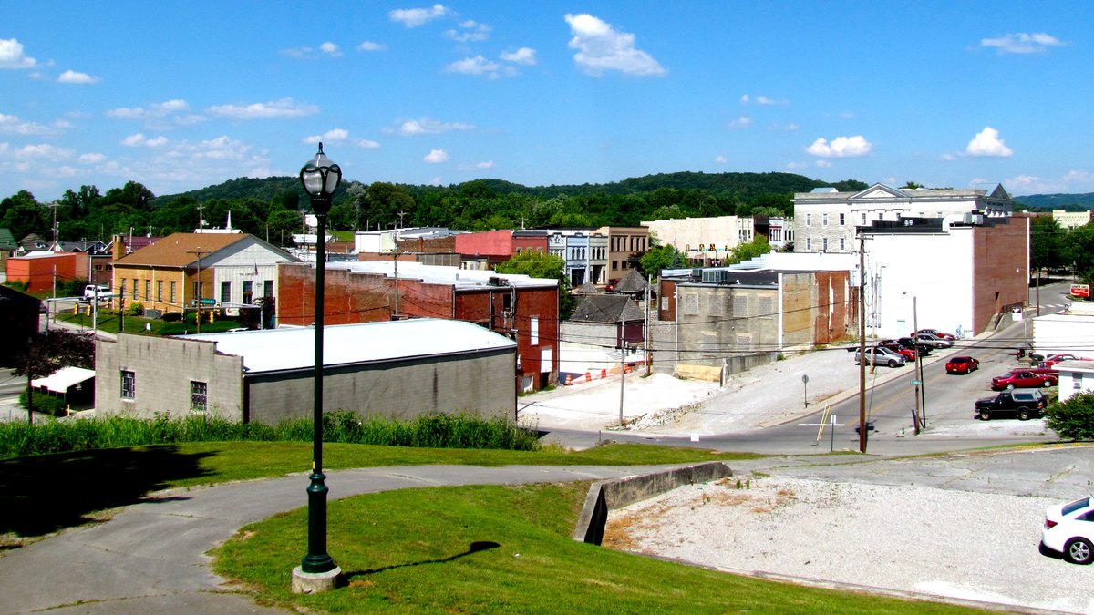 Downtown Sparta, Tennessee, with brick commercial buildings and wooded hills under a blue sky